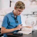 A young adult reviewing student loan statements and calculation sheets to reduce monthly payments.