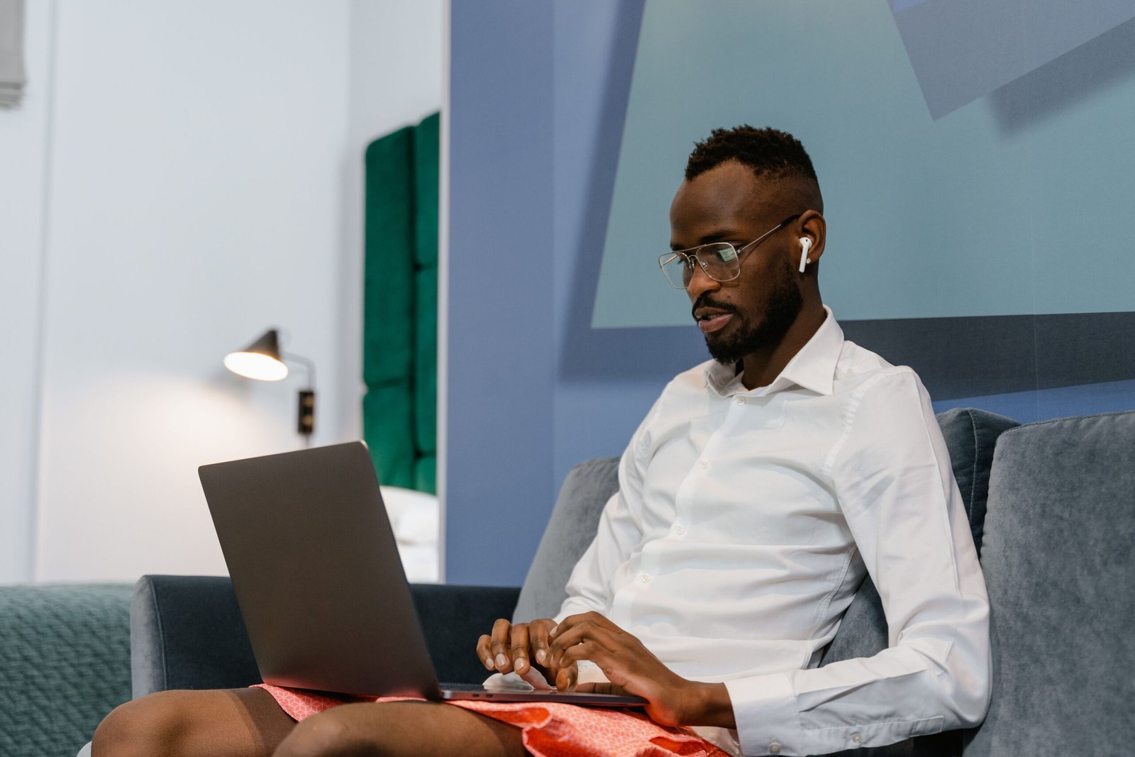 A university student working remotely on his laptop from a couch representing flexible side hustles
