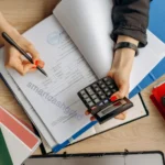 Is Student Loan Forgiveness Taxable in 2026? The Reality of the New "Tax Bomb" A close-up of a person holding an IRS 1099-C tax form next to an open laptop and a student loan statement